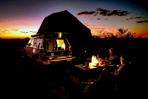 Camping in a van at sunset with bonfire in the Australian desert