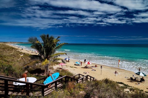 Beach with coconut trees, wooden walkway and colorful umbrellas on Cable Beach, Broome, Western