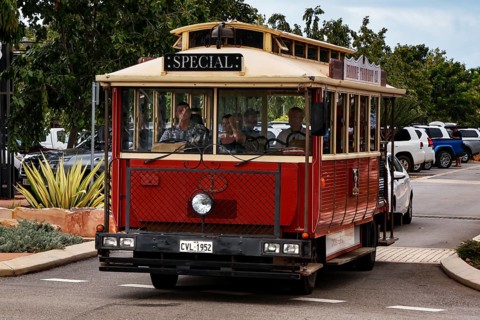 Red tourist bus on Carnarvon Street surrounded by trees, Broome, Western Australia, Australia
