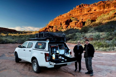 Off-road vehicle having breakfast break in front of impressive rocky backdrop in morning light,