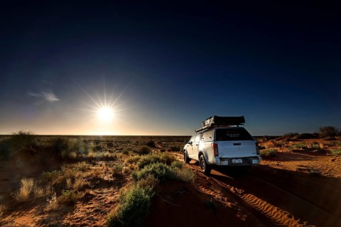 Off-road vehicle on sandy track in Simpson Desert, illuminated by sunrise, Simpson Desert, Northern