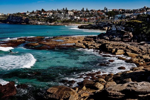 Tamarama Point with rocky shores and clear waves off coast occupied by houses, Sydney, New South