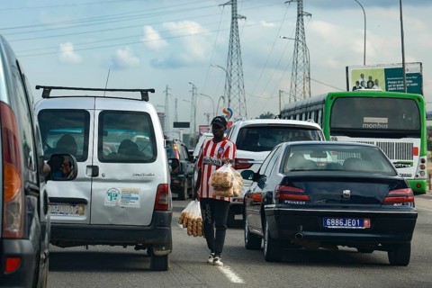 Hustle and bustle in Abidjan with cars stuck in traffic and a person crossing the road, Abidjan,