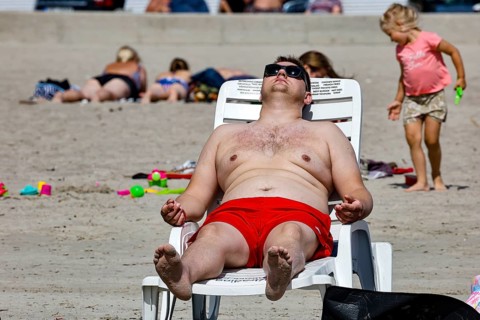 A man wearing red swimming trunks is relaxing on a lounger on a sandy beach, Pärnu, Estonia