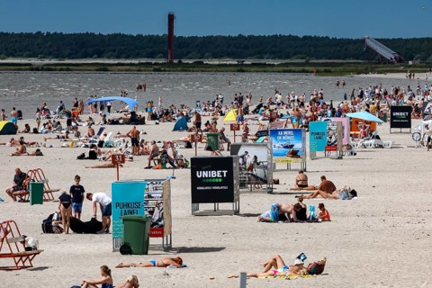 Busy sandy beach with lots of people and advertising signs under clear skies, Pärnu, Pärnu County,