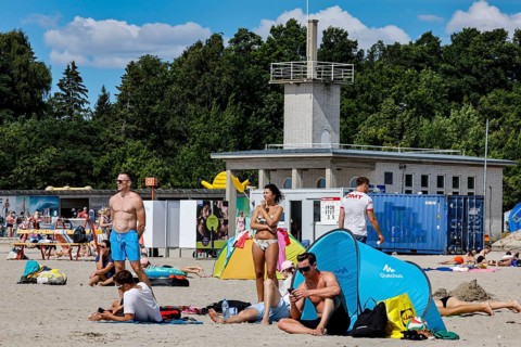 Beach life with tents and a large building in the background in sunny weather, Pärnu, Pärnu County,