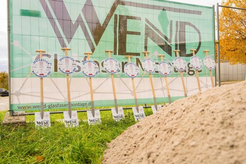 Signs announcing a broadband expansion are lined up in front of a construction fence, fibreglass