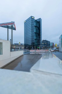 Modern Bitzer high-rise building at dusk with glass façade and a construction site in the