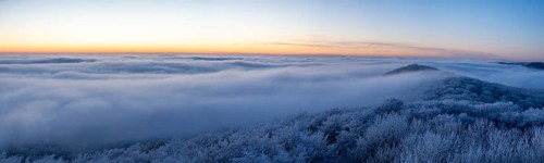 Wide, snowy landscape under a calm sky at dusk, panoramic view of the Teutoburg Forest from an