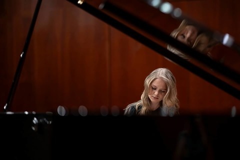 Young woman, pianist, with concentrated facial expression playing on a Steinway & Sons grand piano,