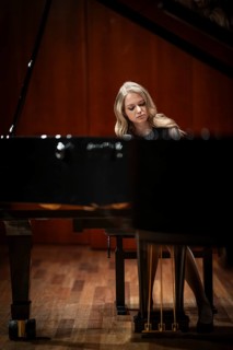 Young woman, pianist, with concentrated facial expression playing on a Steinway & Sons grand piano,