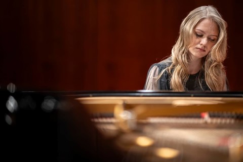 Young woman, pianist, with concentrated facial expression and closed eyes playing on a Steinway &