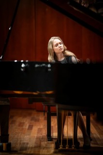 Young woman, pianist, with concentrated facial expression and closed eyes playing on a Steinway &