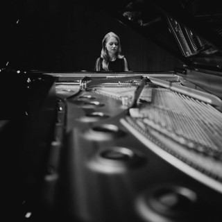Young woman, pianist playing on an opened Steinway & Sons grand piano, black and white photo,