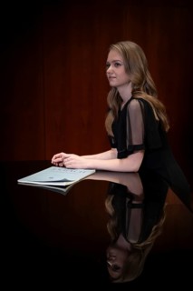 Young woman, pianist, in evening dress, with notes by Johann Sebastian Bach, supported on Steinway