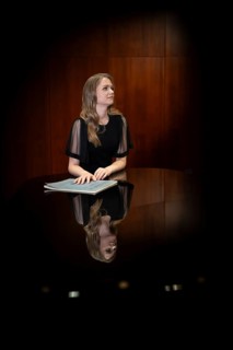 Young woman, pianist, with notes by Johann Sebastian Bach in concert hall, supported on Steinway &