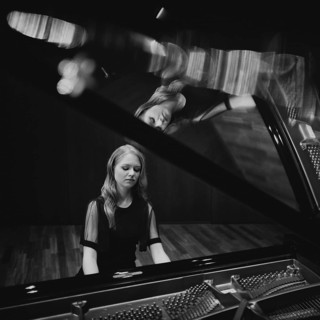 Young woman, pianist, in evening dress playing on an unfolded Steinway & Sons grand piano, black