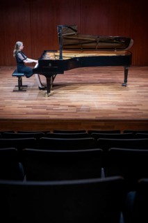 Young woman, pianist, in evening dress, in a concert hall, playing on a Steinway & Sons grand