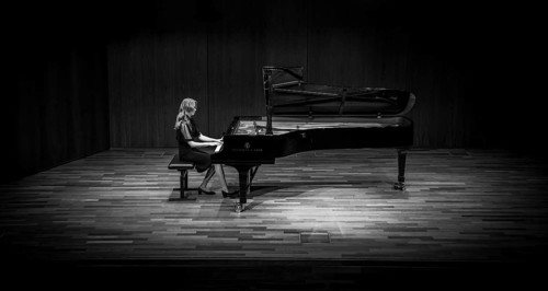 Young woman, pianist, in evening dress, in a concert hall, playing on a Steinway & Sons grand