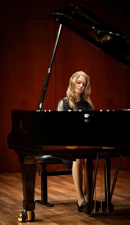 Young woman, pianist, with concentrated facial expression in a concert hall playing a Steinway &