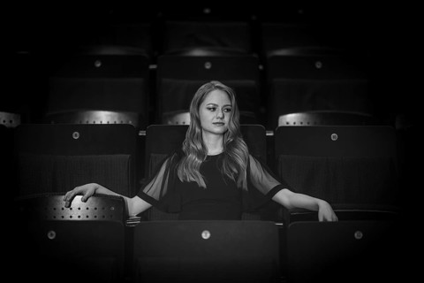 Young woman, pianist, in evening dress, sitting on chair in audience area, Stuttgart,