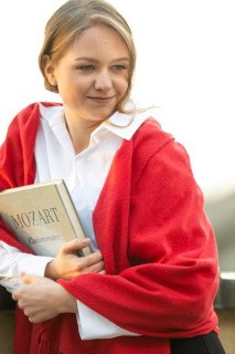 Self-confidently looking young woman, pianist, in white blouse and red cardigan, in the evening