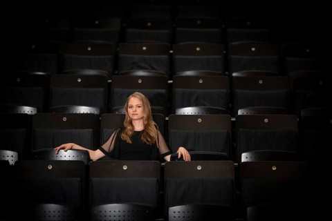 Young woman, pianist, in evening dress, sitting on chair in audience area, Stuttgart,