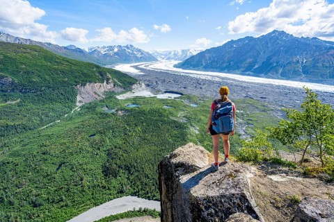 Young woman on a rocky outcrop enjoying the view, view of impressive mountain landscape with