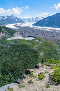Young woman on a rocky outcrop enjoying the view, view of impressive mountain landscape with