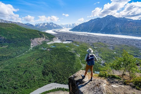 Young man on a rocky outcrop enjoying the view, view of impressive mountain scenery with Matanuska