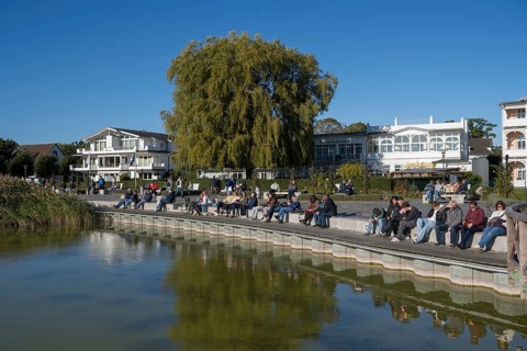 Tourists sunbathe on the promenade, Schmachter See, spa architecture buildings in the back, Binz,