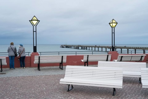 Kurplatz am spa hotel, two people from behind, pier and Baltic Sea behind, twilight, Binz, seaside
