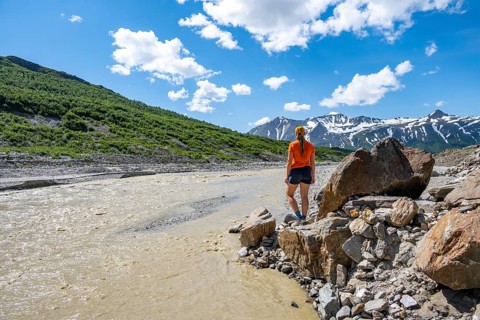 Tourist enjoying views of Miller Creek meltwater river at Castner Glacier, Delta Range, Alaska
