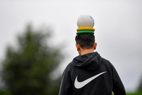 Person with a ball and rings on their head, outside in hoodie, sports and fun Olympics Sportfest