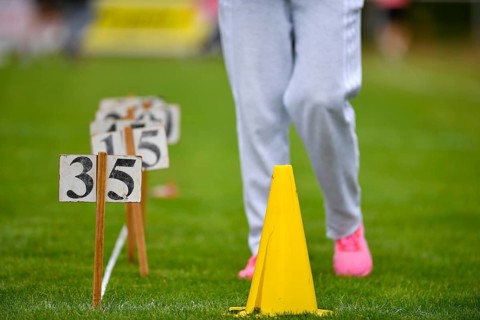 Person on grass with yellow hat and numbers, sporting activity, sports and fun Olympics Sportfest