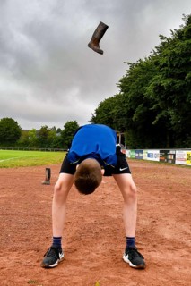 A boy throws a rubber boot high in the air on a sports field rubber boot long throw, sports and fun