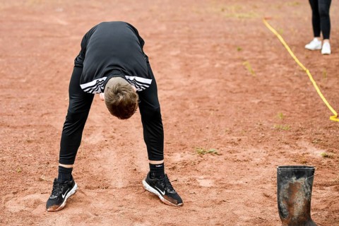 A teenager in sportswear throws a rubber boot on an ash track rubber boots long throw sports and