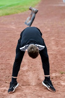 A teenager in sportswear throws a rubber boot on an ash track rubber boots long throw sports and