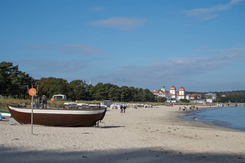 Boat with fishing flags is lying on a sandy beach, behind the spa hotel, Binz, seaside resort,