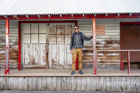 Young man standing on the porch of a former Gold Mine Independence Mine building in mountainous