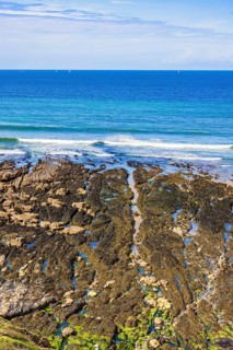 Rocky seashore in low tide with a seascape view to the horizon on a sunny summer day, Crozon