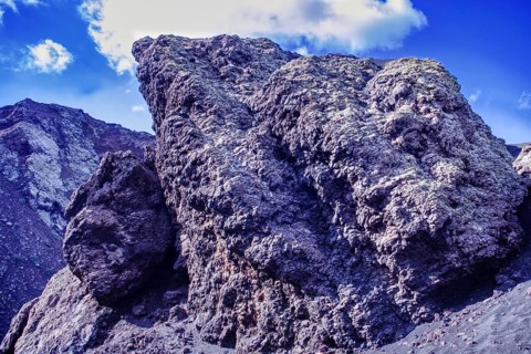 Impressive rock formation of volcanic rock rising against a blue sky, partial view of El Cuervo