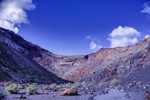 Impressive volcano crater with low vegetation under a blue sky, El Cuervo, Tinajo Lanzarote