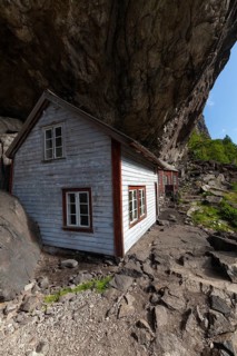 Historical wooden houses sheltered under a massive rock overhang. Summer, Helleren (Helleren),