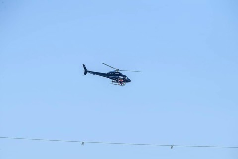 A helicopter flies over a high-voltage line in the air during technical work, Lemförde, Lower