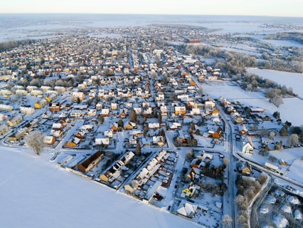 Overview of a snowy village with houses and surrounding fields in the evening light, Aerial View,