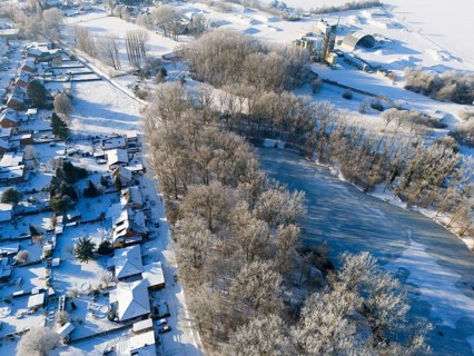 Snowy landscape with a frozen pond, trees and adjacent houses, aerial view, Oelsburg, Ilsede, Peine