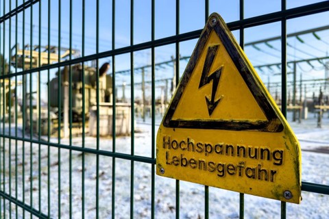 Recording of snow in winter warning sign warning high voltage danger to life on fence from behind