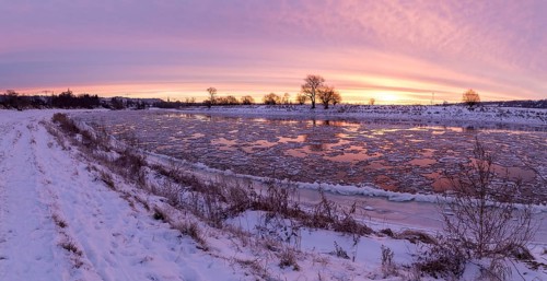 Panorama on a cold winter morning on the Elbe with floating ice floes, snow and dawn at sunrise,