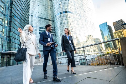 Diverse business professionals walking and discussing in a modern urban city, collaborating and